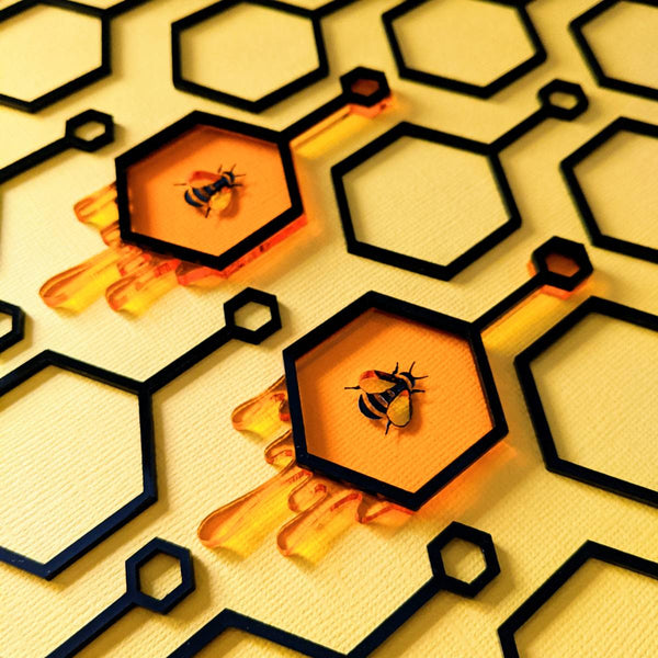 Statement earrings made from honey coloured laser cut acrylic featuring honeycomb, dripping honey and honey bee encased in black hexagon