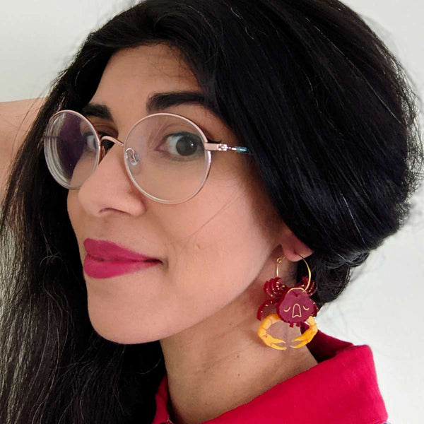 woman wearing red and yellow blue swimmer crab acrylic hoop earrings