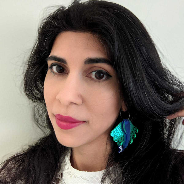 woman wearing royal blue and mirror green peacock acrylic hoop earrings