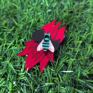 Beautiful red Sturt Desert Pea brooch on a green grassy background with a blue banded bee