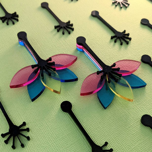 Statement jewellery featuring flower earrings with three transparent petal colours on a slim sturdy black stem